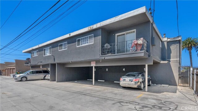1850 Gardenia Ave, Long Beach, CA 90806 - view of front facade featuring a balcony, stucco siding, and a parking lot
