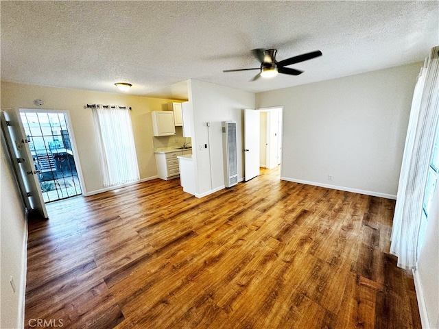 1850 Gardenia Ave, Long Beach, CA 90806 - unfurnished living room with a textured ceiling, wood finished floors, a heating unit, baseboards, and ceiling fan