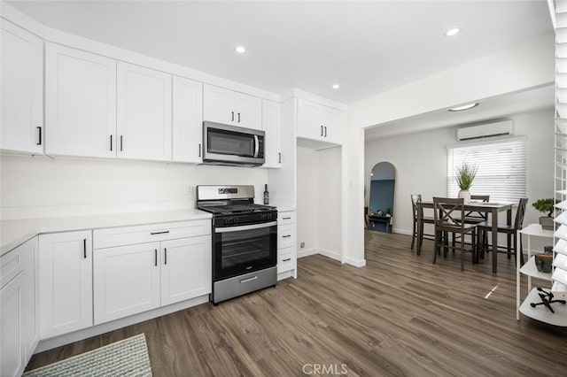 6082 Bannock Rd, Westminster, CA 92683 - kitchen featuring appliances with stainless steel finishes, a wall mounted air conditioner, dark wood-type flooring, light countertops, and white cabinets
