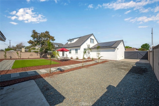 6082 Bannock Rd, Westminster, CA 92683 - view of front of house with a gate, solar panels, a patio area, and stucco siding