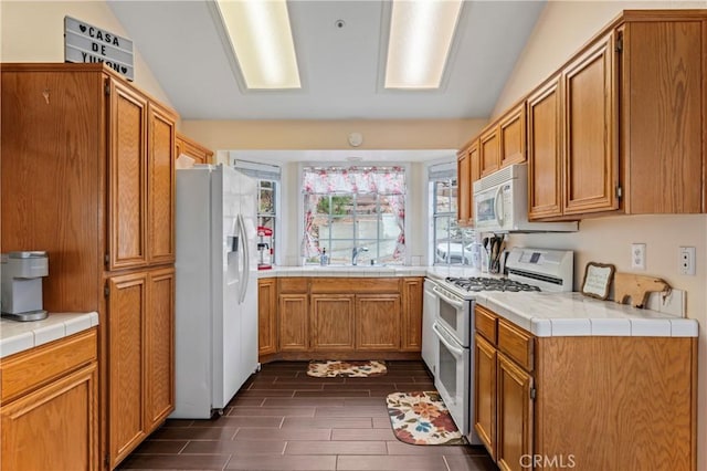 1285 Yukon Dr, Lake Arrowhead, CA 92352 - kitchen with white appliances, vaulted ceiling, brown cabinetry, wood finish floors, and tile counters