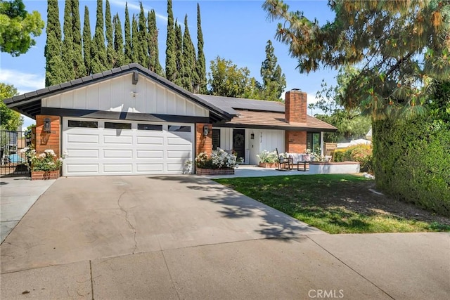 7612 Vicky Ave, West Hills, CA 91304 - view of front of house with a chimney, an attached garage, board and batten siding, solar panels, and driveway