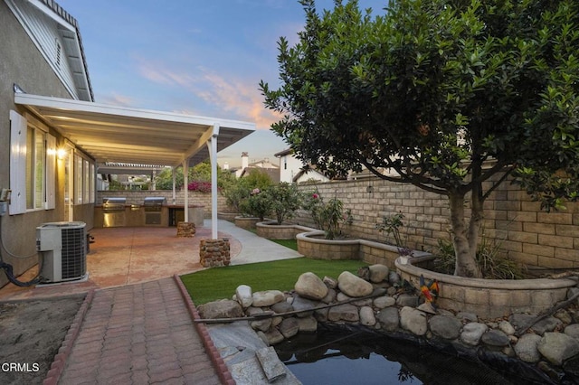 3806 Golden Pond Dr, Camarillo, CA 93012 - patio terrace at dusk featuring a patio area, a fenced backyard, cooling unit, and exterior kitchen