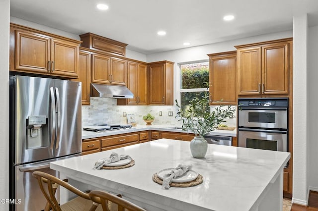 3806 Golden Pond Dr, Camarillo, CA 93012 - kitchen featuring stainless steel appliances, under cabinet range hood, backsplash, recessed lighting, and a kitchen breakfast bar
