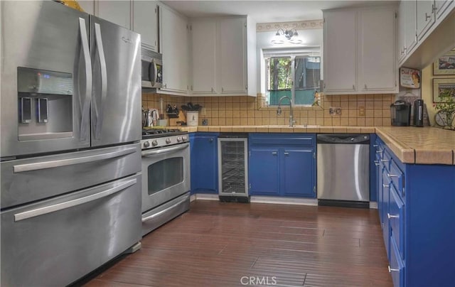1353 Golden Rule Ln, Lake Arrowhead, CA 92352 - kitchen featuring stainless steel appliances, blue cabinetry, wine cooler, dark wood-style flooring, and tasteful backsplash