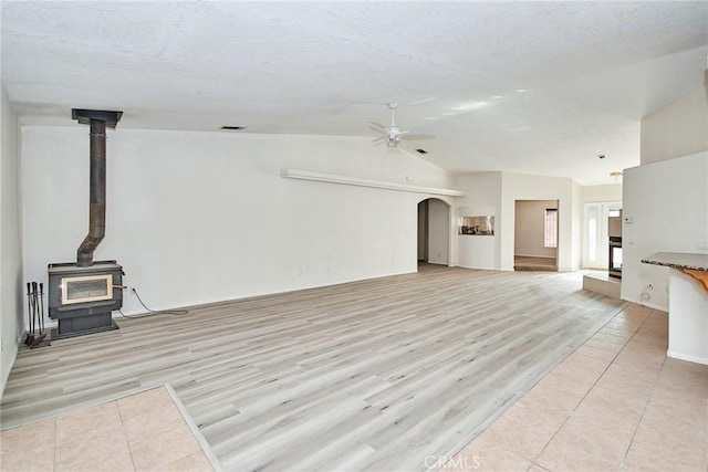 9920 Sage St, Oak Hills, CA 92344 - unfurnished living room with a wood stove, ceiling fan, light wood-style floors, lofted ceiling, and arched walkways