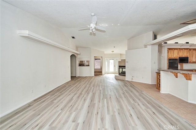 9920 Sage St, Oak Hills, CA 92344 - unfurnished living room featuring ceiling fan, vaulted ceiling, light wood-type flooring, baseboards, and arched walkways