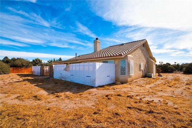 9920 Sage St, Oak Hills, CA 92344 - rear view of property with a chimney, stucco siding, a tiled roof, and cooling unit