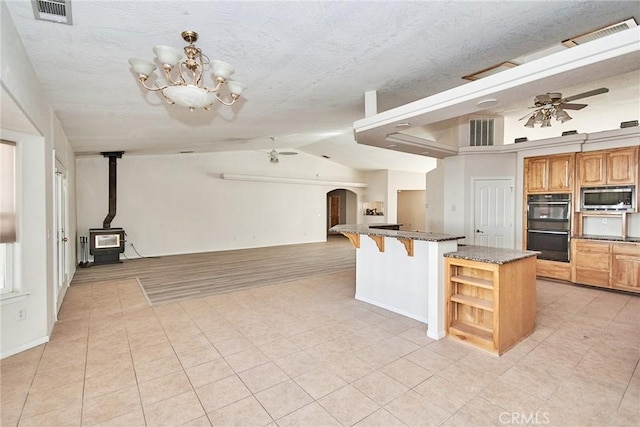 9920 Sage St, Oak Hills, CA 92344 - kitchen featuring stainless steel microwave, a wood stove, a ceiling fan, light tile patterned flooring, and open floor plan