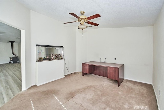 9920 Sage St, Oak Hills, CA 92344 - unfurnished office with a wood stove, a ceiling fan, light carpet, and baseboards