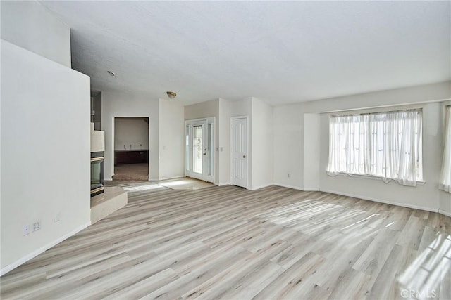 9920 Sage St, Oak Hills, CA 92344 - unfurnished living room featuring plenty of natural light, light wood-type flooring, baseboards, and a glass covered fireplace