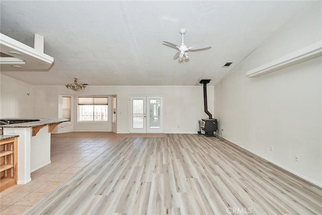 9920 Sage St, Oak Hills, CA 92344 - unfurnished living room featuring a wood stove, a ceiling fan, light wood-type flooring, baseboards, and a chandelier