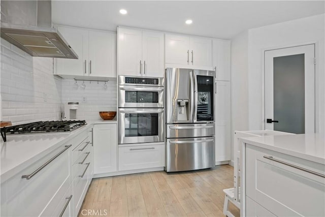 17913 Maplehurst Pl, Canyon Country, CA 91387 - kitchen with appliances with stainless steel finishes, wall chimney range hood, light countertops, white cabinets, and decorative backsplash