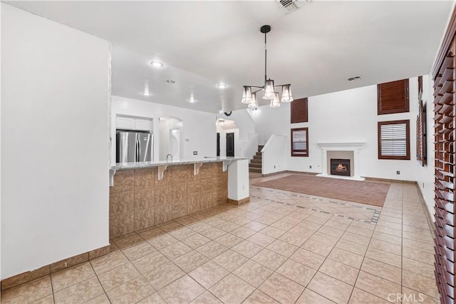2904 Granite Ridge Pl, Bakersfield, CA 93313 - kitchen featuring freestanding refrigerator, light tile patterned floors, a breakfast bar, hanging light fixtures, and light stone counters