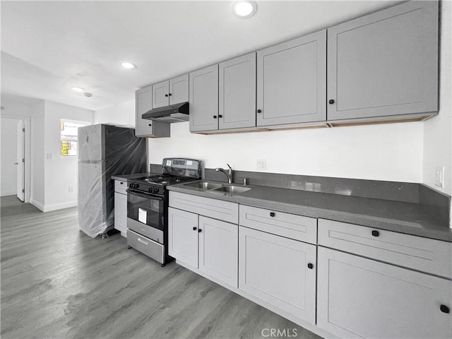 10405 S Hoover St, Los Angeles, CA 90044 - kitchen featuring black gas stove, a sink, under cabinet range hood, light wood finished floors, and dark countertops