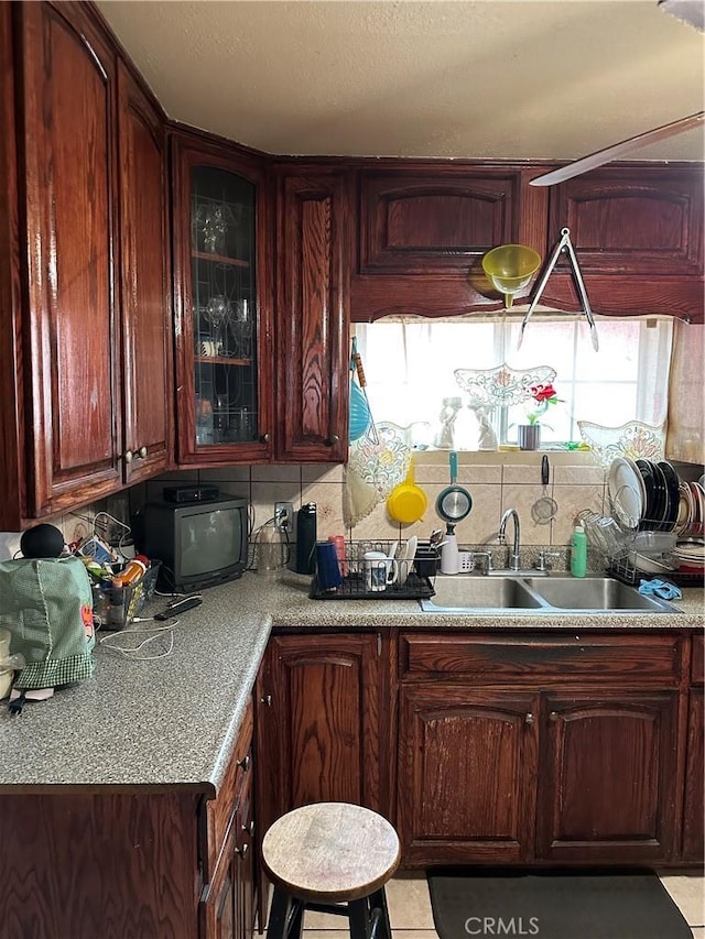 2607 E 135th St, Compton, CA 90222 - kitchen featuring a sink, decorative backsplash, glass insert cabinets, and light countertops