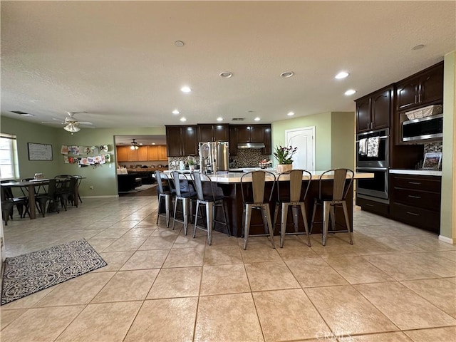 8843 San Diego Dr, Yucca Valley, CA 92284 - kitchen featuring stainless steel appliances, recessed lighting, light tile patterned floors, a breakfast bar area, and tasteful backsplash