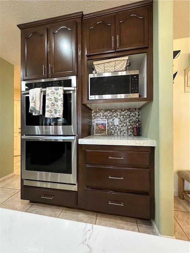 8843 San Diego Dr, Yucca Valley, CA 92284 - kitchen featuring stainless steel appliances, decorative backsplash, light countertops, dark brown cabinetry, and baseboards