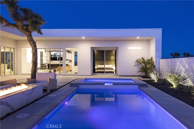 7035 Sunny Vista Rd, Joshua Tree, CA 92252 - back of house at night with a fire pit, stucco siding, a patio area, and a pool with connected hot tub