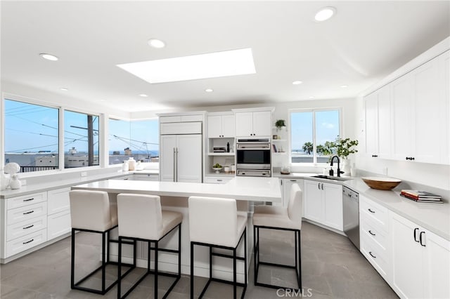 420 34th St, Manhattan Beach, CA 90266 - kitchen with appliances with stainless steel finishes, a kitchen island, a skylight, a breakfast bar, and recessed lighting