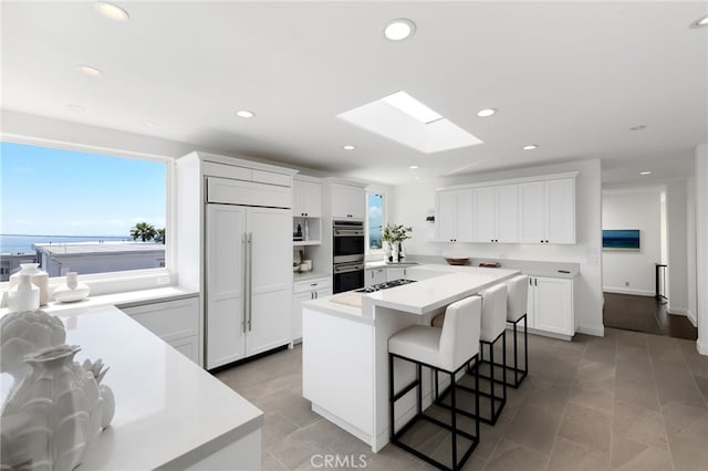 420 34th St, Manhattan Beach, CA 90266 - kitchen with appliances with stainless steel finishes, a skylight, a center island, a breakfast bar area, and white cabinetry