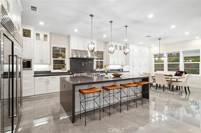 56 Claudius Ct, Irvine, CA 92618 - kitchen with light marble finish floors, dark countertops, under cabinet range hood, stainless steel built in fridge, and a kitchen breakfast bar