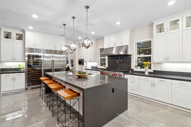 56 Claudius Ct, Irvine, CA 92618 - kitchen with under cabinet range hood, light marble finish floors, dark countertops, stove, and stainless steel built in refrigerator