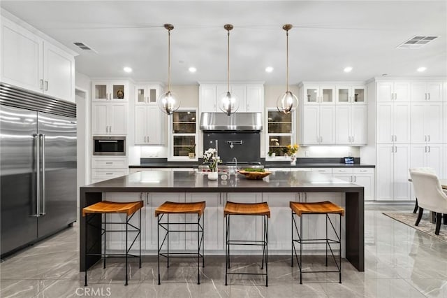 56 Claudius Ct, Irvine, CA 92618 - kitchen with built in fridge, dark countertops, under cabinet range hood, white cabinets, and recessed lighting