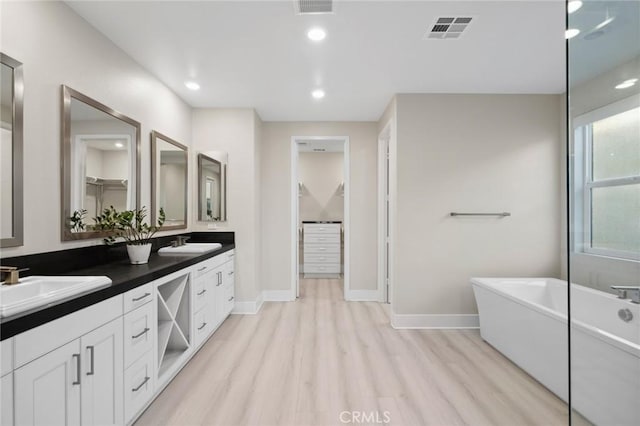 56 Claudius Ct, Irvine, CA 92618 - bathroom featuring double vanity, a freestanding tub, wood finished floors, baseboards, and recessed lighting