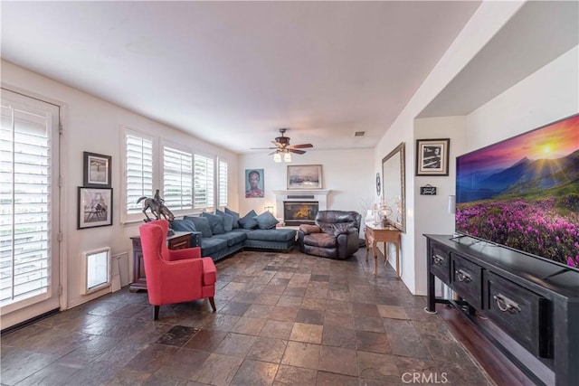 668 Corte Sol, Camarillo, CA 93010 - living room with dark stone finish floors, a glass covered fireplace, and a ceiling fan