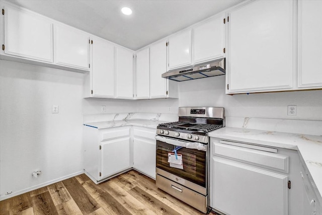1036 W Gilman St, Banning, CA 92220 - kitchen with stainless steel gas range oven, under cabinet range hood, white cabinets, light wood finished floors, and recessed lighting