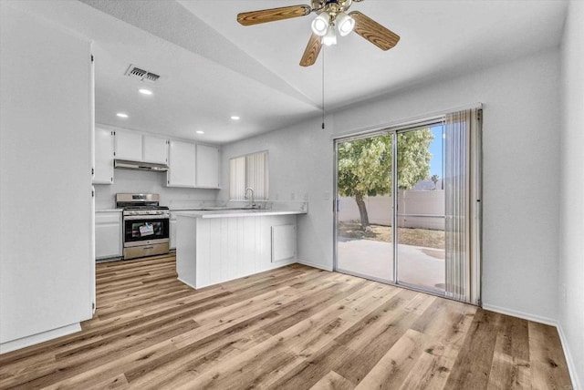 1036 W Gilman St, Banning, CA 92220 - kitchen featuring gas stove, light countertops, light wood-style floors, under cabinet range hood, and a peninsula