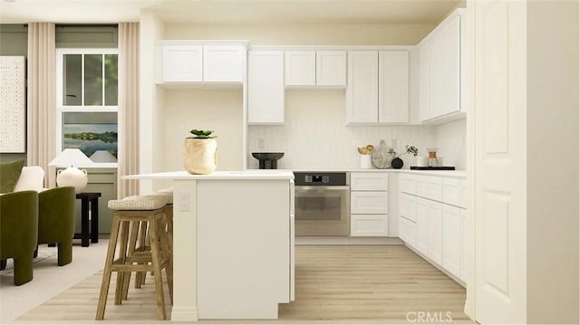 1630 Eagle Rd, Rialto, CA 92376 - kitchen featuring oven, white cabinetry, a kitchen island, a breakfast bar area, and light countertops