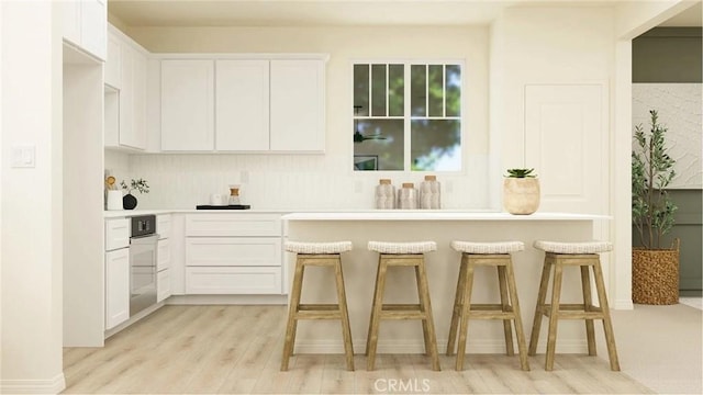 1630 Eagle Rd, Rialto, CA 92376 - kitchen with a kitchen breakfast bar, light wood-type flooring, white cabinets, and light countertops