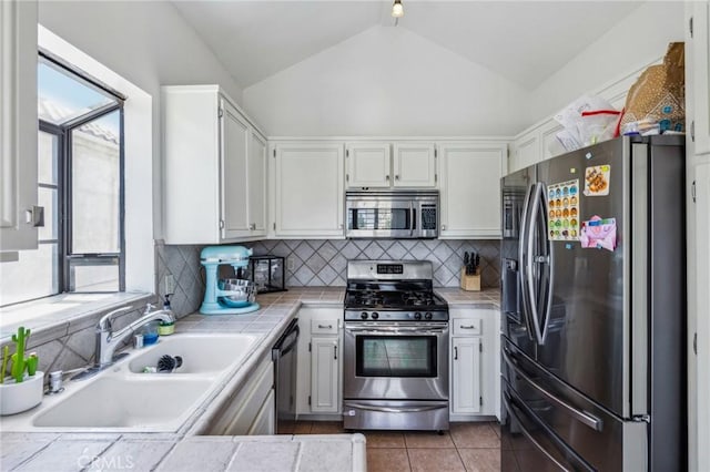 18107 Erik Ct Unit 462, Canyon Country, CA 91387 - kitchen with appliances with stainless steel finishes, tile countertops, a sink, vaulted ceiling, and decorative backsplash