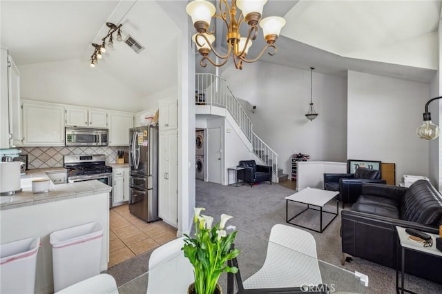 18107 Erik Ct Unit 462, Canyon Country, CA 91387 - living area featuring rail lighting, estacked washer and dryer, a chandelier, stairway, and high vaulted ceiling