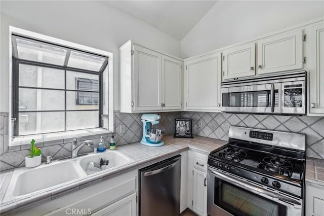 18107 Erik Ct Unit 462, Canyon Country, CA 91387 - kitchen with stainless steel appliances, a sink, lofted ceiling, decorative backsplash, and tile counters