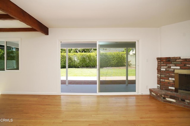 513 E Comstock Ave, Glendora, CA 91741 - unfurnished living room featuring healthy amount of natural light, beam ceiling, light wood-style flooring, and a brick fireplace
