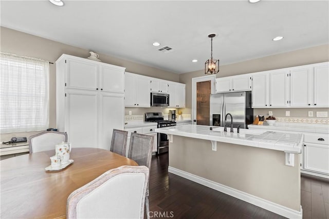 28409 Connick Pl, Saugus, CA 91350 - kitchen with appliances with stainless steel finishes, white cabinetry, dark wood finished floors, an island with sink, and recessed lighting