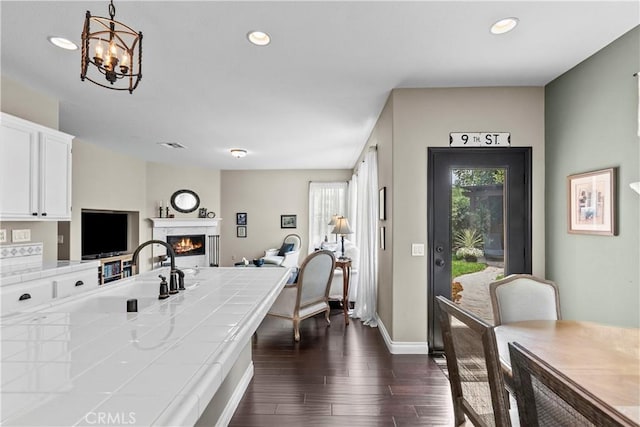 28409 Connick Pl, Saugus, CA 91350 - kitchen featuring tile counters, dark wood-type flooring, a lit fireplace, white cabinetry, and open floor plan