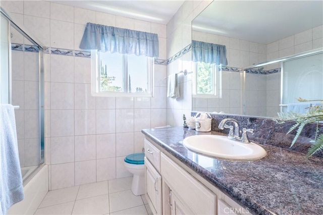 11811 Louise Ave, Granada Hills, CA 91344 - bathroom featuring vanity, toilet, tile patterned floors, tile walls, and bath / shower combo with glass door