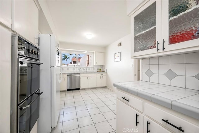 20 Mandrake Way, Irvine, CA 92612 - kitchen featuring stainless steel dishwasher, decorative backsplash, light tile patterned floors, white cabinetry, and freestanding refrigerator