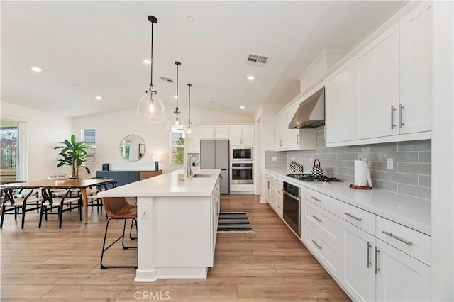 1890 Pele Way, Corona, CA 92882 - kitchen with wall chimney exhaust hood, vaulted ceiling, tasteful backsplash, gas cooktop, and white cabinetry