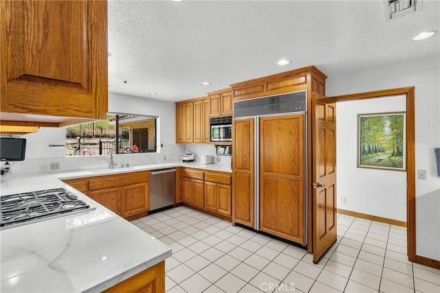 52 Hidden Valley Rd, Monrovia, CA 91016 - kitchen featuring stainless steel appliances, light countertops, brown cabinetry, recessed lighting, and light tile patterned floors