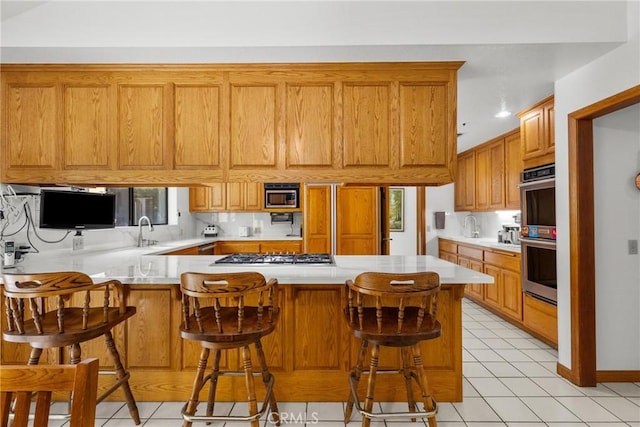 52 Hidden Valley Rd, Monrovia, CA 91016 - kitchen featuring stainless steel appliances, light countertops, a peninsula, and brown cabinetry