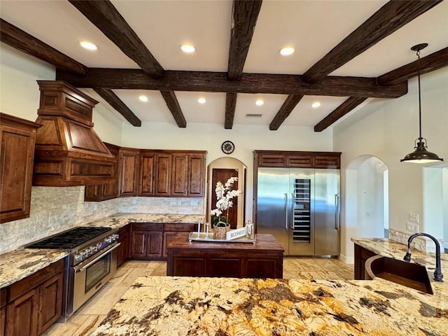 1415 Via Vallarta, Riverside, CA 92506 - kitchen with refrigerator, high end stainless steel range, backsplash, arched walkways, and beam ceiling