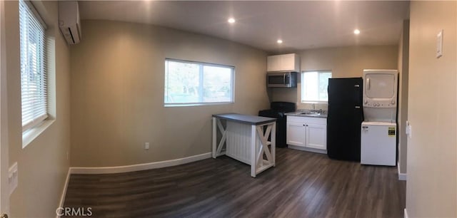 10022 Gothic Ave, North Hills, CA 91343 - kitchen featuring stainless steel microwave, stacked washing machine and dryer, black range, white cabinets, and dark wood finished floors