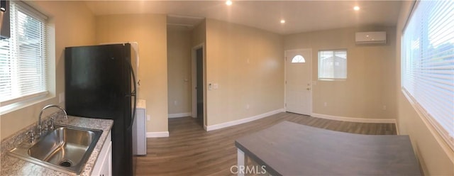 10022 Gothic Ave, North Hills, CA 91343 - kitchen featuring freestanding refrigerator, a sink, dark wood-type flooring, a wall mounted air conditioner, and baseboards