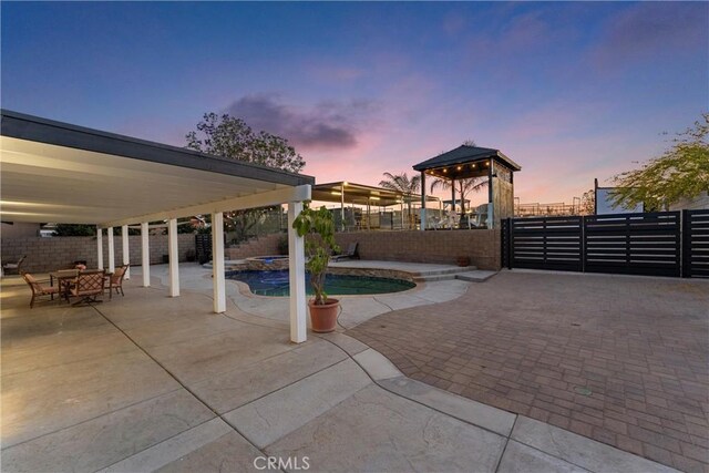 5080 Pinto Pl, Norco, CA 92860 - patio terrace at dusk with a fenced backyard, a gazebo, a patio, and a pool with connected hot tub