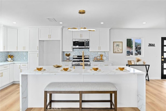 5080 Pinto Pl, Norco, CA 92860 - kitchen featuring stainless steel appliances, tasteful backsplash, white cabinets, light wood-style floors, and pendant lighting